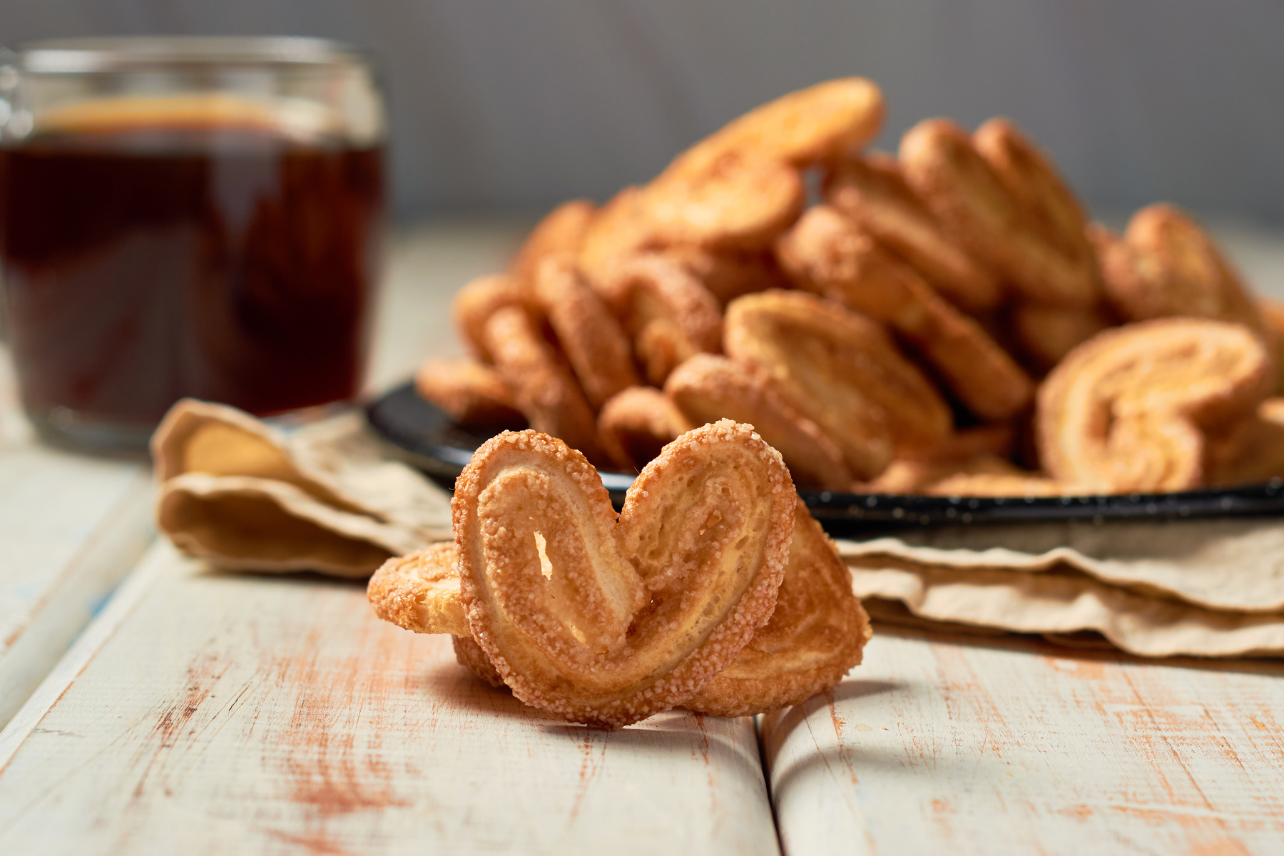 Puff pastry cookies palmier or elephant ears, caramelized and crunchy pastry with coffee. Focus Selective